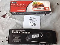 Two digital kitchen meat thermometers with packaging: D&M Digital Food Thermometer and black Waterproof Meat Thermometer in boxes.