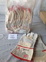 One dozen large size 10 work gloves in clear plastic packaging, with one glove laid out to show markings and construction.