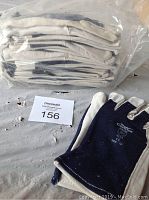 Twelve pairs of Condor size 10 work gloves stacked in a sealed plastic bag, with one pair displayed beside it on a table.