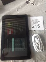 Photo showing RCA Android tablet on activation screen alongside white micro USB charging cable and Maxsold auction tag 215