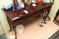 Front view showing single drawer with brass handle and curved legs