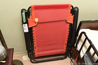 Folded view of the patio lounger chair showing metal frame and red fabric folded flat.