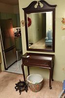Mirror mounted on wall above hall table in living area, refrigerator visible to left.