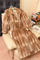 Brown Leader brand fur coat hanging on chair, showing full length and texture of fur