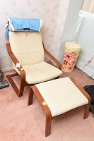 Full view of chair and foot stool side by side on carpet showing overall shape, upholstery, and wooden frame.