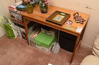 Wooden table with items on top including vases, framed art, figurine, and pinwheel, along with boxes underneath.