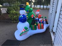 Full view of the inflatable showing two snowmen, Christmas tree, presents, penguins, candy cane, and polarized base.