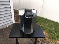 Front view of the Keurig B70 coffee maker showing control panel, water reservoir, and drip tray
