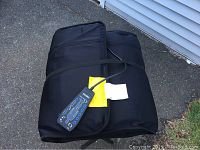 Black Homedics massage chair in carrying case with attached wired remote control.