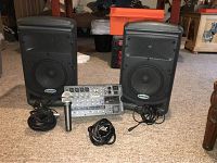 Overview of two speakers, central mixer, microphone and cables laid out on carpet