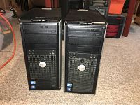 Front view showing two Dell Optiplex 380 black desktop towers side by side on carpeted floor.