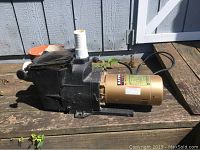 Side view of Hayward Super Pump showing black pump housing and attached gold motor on wooden surface outdoors.