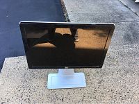 Front view of HP W2207 monitor showing screen and stand on a concrete surface outdoors.