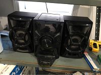 Sony MHC-EC609IP speaker system with main unit and two satellite speakers on a table.