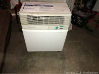 Front view of the portable air conditioner unit showing vent, control knob, and lower storage area.