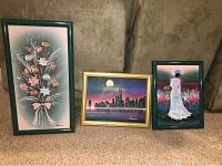 Three textured paintings by Hansen, showing a floral bouquet, cityscape at night, and a woman in a garden, arranged on a carpeted floor