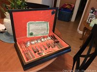 Full view of opened box showing the silverplate flatware set organized inside and the certificate affixed inside lid.