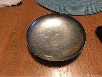 Top view of round sterling silver plate showing shallow bowl and reflective surface with scratches.
