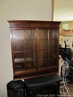 Front view of the wooden display cabinet with glass sliding doors showing entire cabinet and shelves inside