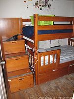 Bunk bed front side view showing upper and lower bunks, side stairs with storage drawers, and mattresses on bunks.
