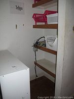 Photo of wooden cubby storage unit positioned against wall with some electronic device and cords on bottom shelves.