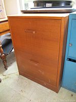 Front view of wooden filing cabinet showing two drawers and wood grain finish.