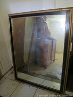 Full view of the standing rectangular wall mirror showing reflective surface and frame condition.