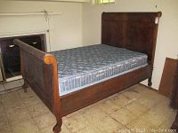 Full wooden bed frame assembled with mattress, showing headboard and side view with wear marks.