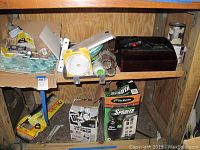 Wide shelf view showing multiple boxes and items including the sprayer box, caulk, tubes, tiles and tubing.
