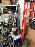 Wooden shelving unit with various stored items including tripod, chemicals, and small containers