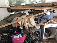 Image showing the wooden workbench cluttered with automotive mats, wood trims, bicycle parts, and wrapped items on top