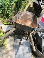 Wheelbarrow with wooden handles, rusted metal bed, showing flat inflatable tire and outdoor storage condition