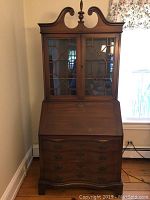 Complete view of the closed mahogany drop front desk with upper glass cabinet, showing overall structure and finish.