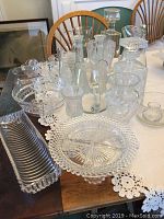 Full view of collection on table showing variety of pitchers, bowls, plates, and coasters with detailed glass patterns.