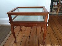 Full side view of the wooden and glass display end table showing legs and glass panels.