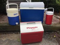 Photo showing all four coolers: a large blue and white chest cooler, a white and red Igloo Playmate chest cooler, a blue and white Coleman beverage cooler, and a red and white beverage cooler.