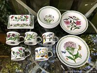 Overview of butter dish, mugs, bowls and plate arranged on glass table