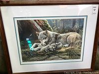 Framed print showing full view of the artwork portraying a wolf with pups in a woodland setting.