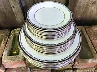 Three stacks of plates on brick ledge against wood fence