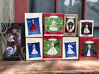 Photo of all eight boxed Hallmark Keepsake Barbie Christmas ornaments arranged on a surface showing different editions and years, color dresses vary.