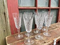 Seven Waterford Crystal stemware glasses displayed outdoors showing detailed diamond cut pattern and clear crystal craftsmanship.