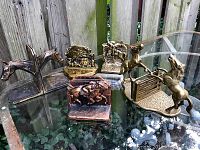 Overview photo showing all equestrian-themed vintage bookends arranged on glass table outdoors. Several bookend pairs featured with horse motifs.