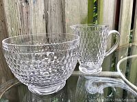 Photo showing the large honeycomb patterned crystal bowl and matching jug together on a glass surface outdoors.