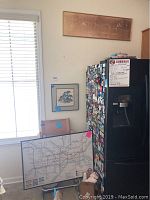 Photo showing three framed wall art pieces including a London Underground map poster leaning against a chair, a Skunk Train framed print on a wall, and a third vintage-style framed art piece also hanging on the wall.