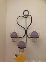 Front view of the metal candle sconce with all three glass holders and purple candles visible, showing the heart shape on top and sconce height.