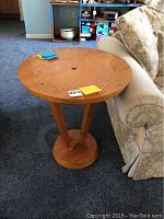 Side view of the wooden round side table showing its height, circular base, and three-leg support structure.