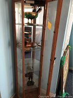 Full view of glass display cabinet holding the items: glass goblet, stereograph slides, and bronze figurine.