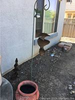 Photo showing large outdoor ceramic planter and metal bird wind chime stand with layered birds hanging
