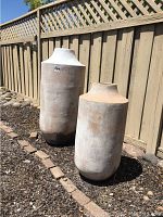 Two large outdoor pots side by side on dirt ground next to a wooden fence, tallest pot around 41 inches