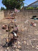 Wide view of outdoor metal art pieces placed on dirt yard with fence background